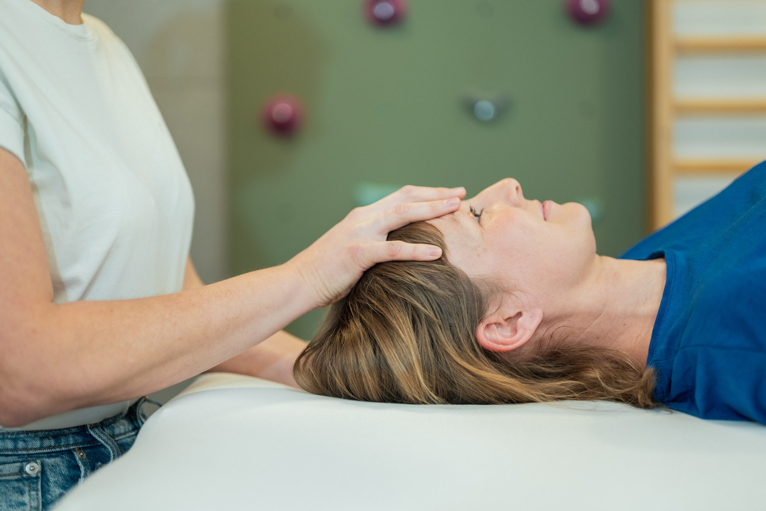 Osteopathische Behandlung mit Hand auf dem Kopf einer Patientin in der Praxisgemeinschaft Weingarten, Feldkirchen an der Donau